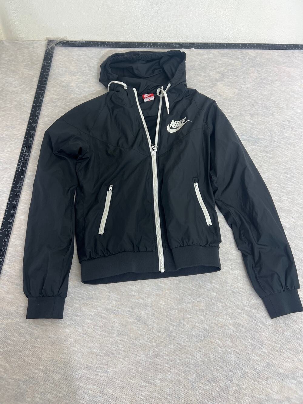 black and white Nike Windrunner jacket w full-zip closure and a hooded design.